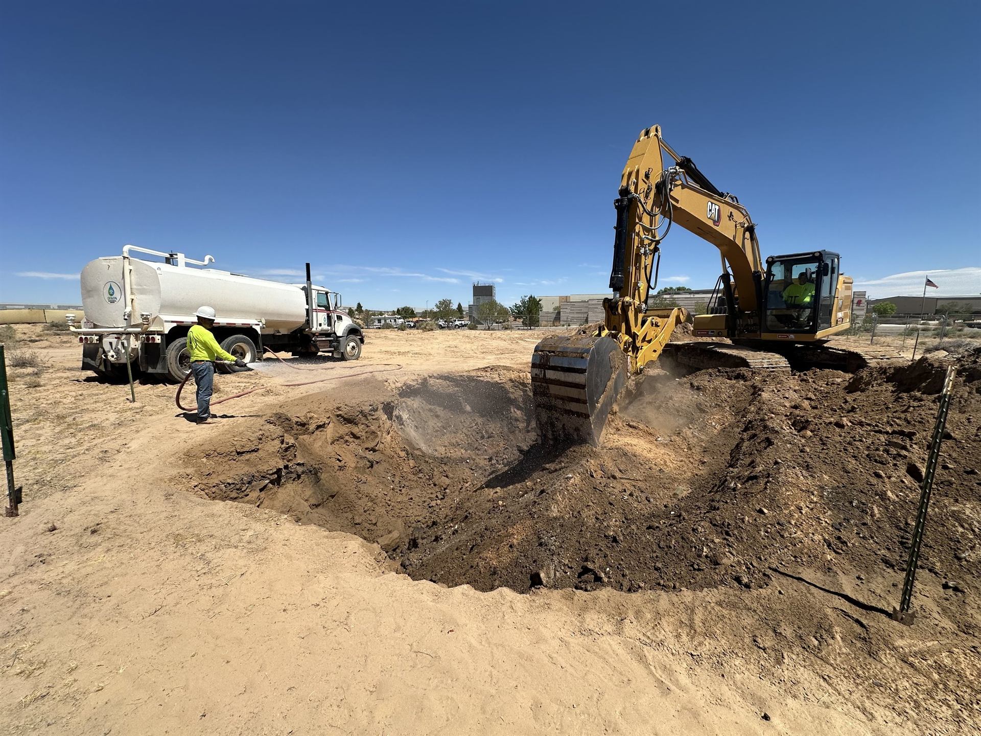 DEKON crew excavating soil with a CAT excavator and water truck for dust suppression in the Four Corners region