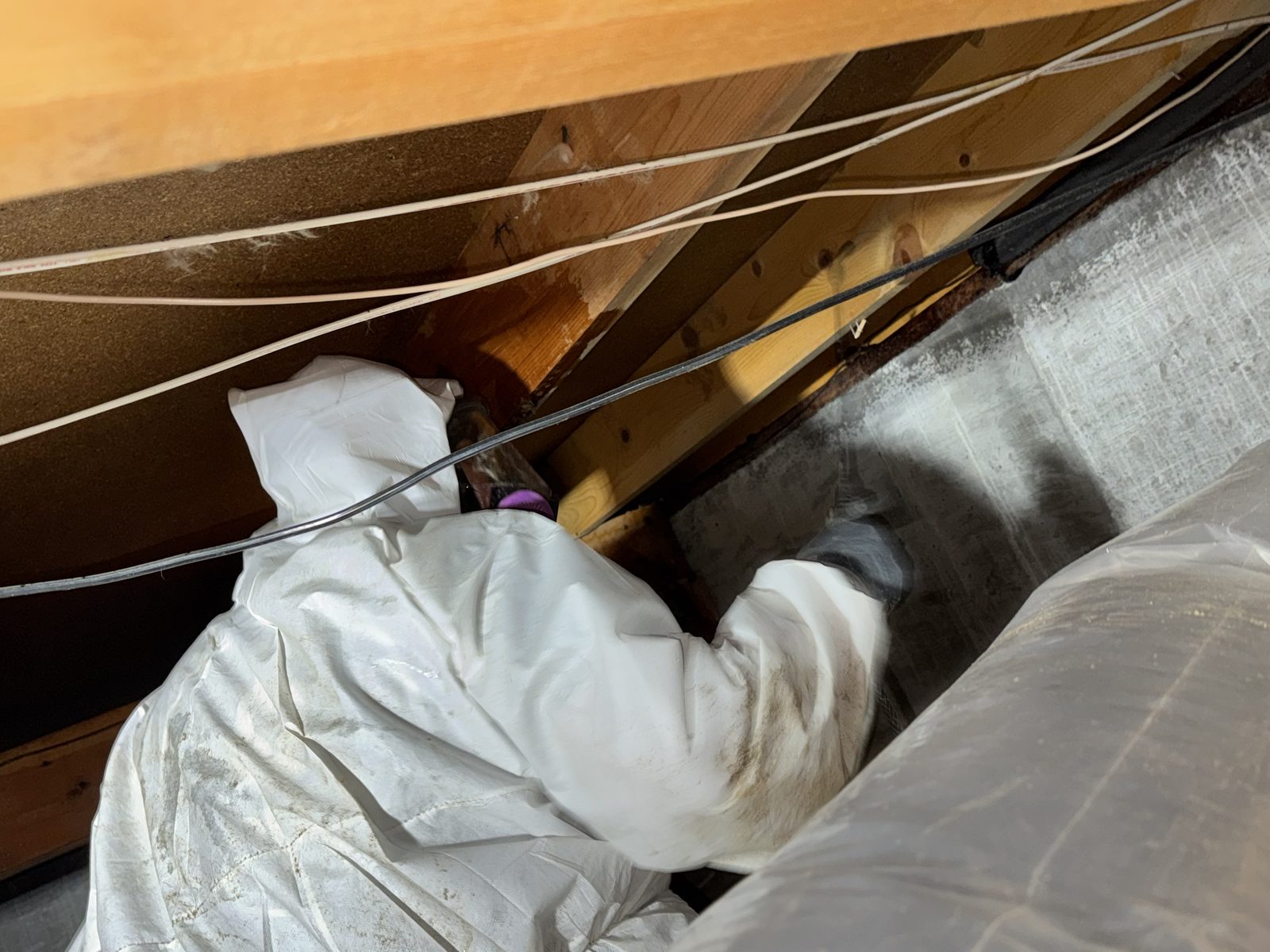 Technician working a crawlspace in PPE