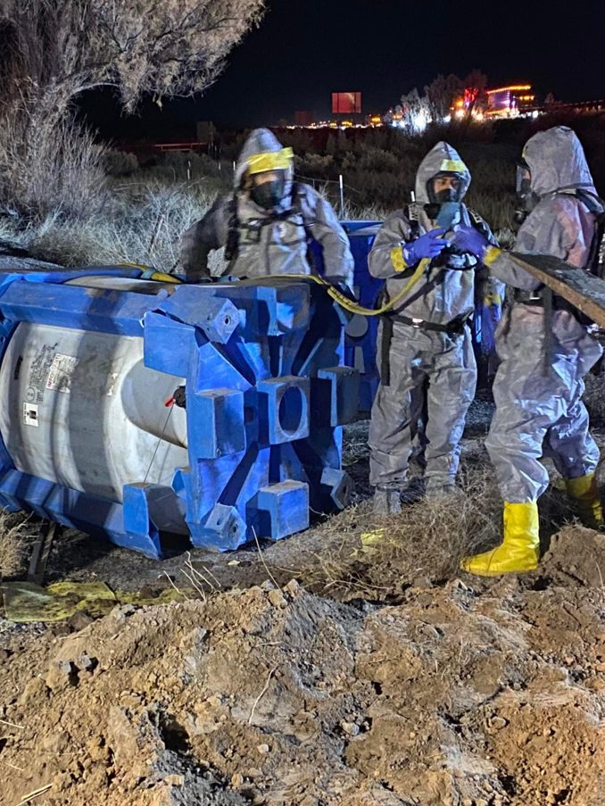 Suited crew working an overturned tanker after dark