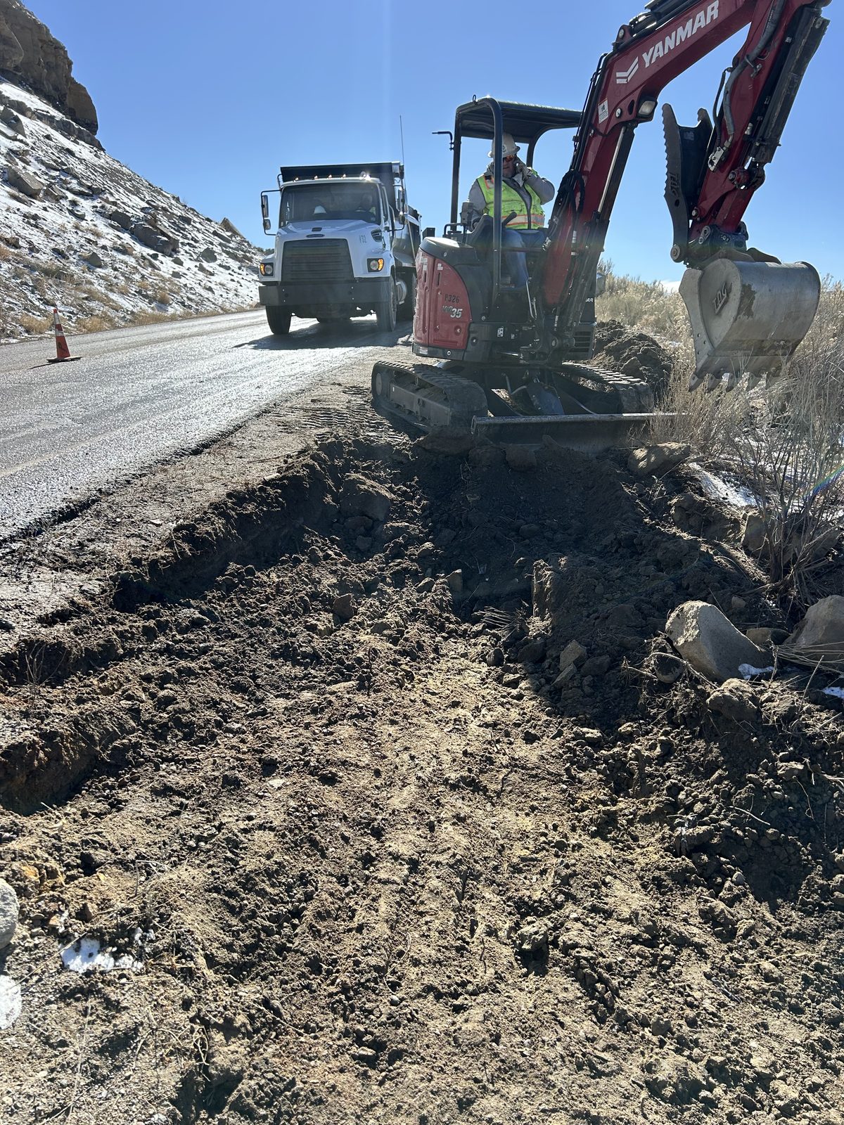 Excavator working the shoulder cut back to clean material
